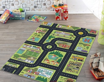May include: A rectangular play rug featuring a city map design with roads, buildings, and green spaces. The rug has a black road network with white dashed lines, and illustrations of a hospital, houses, and a soccer field. The rug is on a wooden floor.