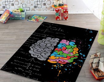May include: Black rectangular area rug featuring a brain graphic. One half of the brain is gray, the other is multi-colored. The rug has mathematical equations and the word "STREET" printed on it.