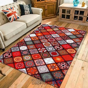 May include: A large, rectangular rug with a patchwork design. The rug features a repeating pattern of squares in shades of red, orange, grey, and white, each with a unique floral or geometric motif. The rug is placed on a wooden floor.