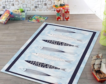 May include: A rectangular rug with a light blue background and a dark blue border. The rug features six stylized fish in black and white, with various patterns. The rug is placed on a wooden floor.