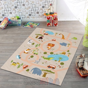 Op de afbeelding: Beige speelmat met een safarithema, met wegen, dieren en auto's. De mat bevat een zebra, giraffe, leeuw, olifant en andere dieren, met een blauwe waterpartij en palmbomen. De wegen zijn lichtoranje.