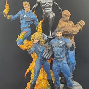 Op de afbeelding: Gedetailleerd beeldje met de personages van de Fantastic Four en Silver Surfer. De figuren staan in dynamische poses, met levendige kleuren en ingewikkelde details. The Thing is een bruin, rotsachtig figuur. Human Torch is omringd door vlammen. Silver Surfer is metallic zilver van kleur.