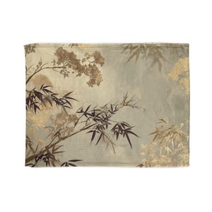 Può includere: Una coperta decorativa rettangolare con un design botanico. Il design include steli e foglie di bambù nei toni del marrone e dell'oro su uno sfondo verde e beige tenui. La coperta ha un aspetto morbido e strutturato.