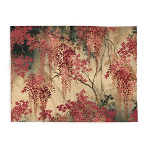 Op de afbeelding: Een rechthoekige plaid met een gedetailleerde botanische print van hangende blauweregenbloemen en esdoornbladeren in tinten dieprood, bordeaux en zachtroze tegen een beige en donkergrijze achtergrond in aquarel-stijl.