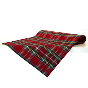 Pode incluir: Um corredor de mesa vermelho e verde xadrez com uma borda xadrez branca e amarela. O corredor está dobrado ao meio e está sobre uma superfície branca.