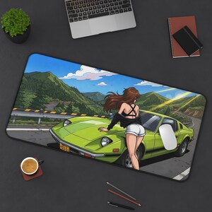 May include: A rectangular desk mat featuring an anime-style illustration of a person with long brown hair leaning against a lime green sports car. The scene depicts a winding mountain road with green hills, a blue sky, and clouds in the background.