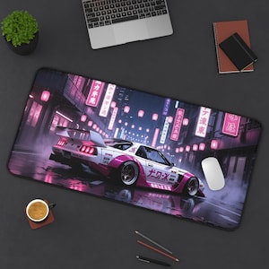 Può includere: Un tappetino per mouse rettangolare con un'auto sportiva bianca e rosa che corre per una strada illuminata al neon. L'auto ha del testo giapponese sul lato. Lo sfondo include lanterne e edifici rosa. Un mouse bianco è a destra.