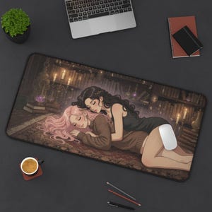 May include: A rectangular desk mat featuring an anime-style illustration of two figures embracing on a rug in a library. One figure has long pink hair and a brown sweater, while the other has long black hair and a black top. A white computer mouse rests on the mat.
