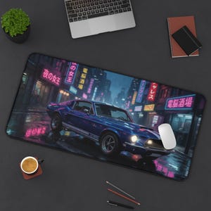 Può includere: Un tappetino da scrivania rettangolare con un'auto sportiva vintage blu parcheggiata su una strada cittadina bagnata di notte. Lo sfondo mostra edifici con insegne al neon giapponesi rosa e blu. Un mouse bianco è appoggiato sulla superficie.