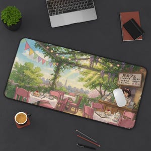 May include: A rectangular desk mat featuring an anime-style illustration of an outdoor cafe terrace with pink chairs, tables, string lights, and a menu board with Japanese text. The scene depicts a garden setting with trees and a distant cityscape.