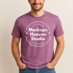May include: A short-sleeved, heathered purple t-shirt. The shirt features a white circular graphic with the text "Perfect mockups Mockups Heaven Studio Perfect designs". The person is wearing blue jeans.