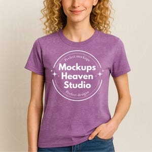 Puede incluir: Una camiseta morada con cuello redondo y mangas cortas. La camiseta presenta un logotipo circular blanco con el texto "Perfect mockups, Mockups Heaven Studio, Perfect designs". La modelo lleva vaqueros azules.