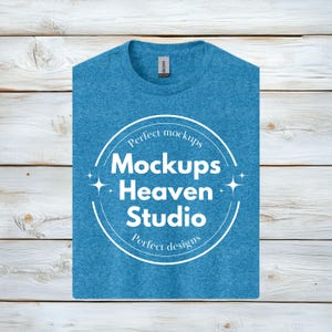 以下が含まれることがあります： 白い円形のロゴがついた青いヘザーのTシャツ。ロゴには「Perfect mockups Mockups Heaven Studio Perfect designs」と書いてあります。