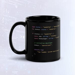 以下が含まれることがあります： カラフルなプログラミングコードのテキストがプリントされた黒いセラミック製マグカップ。テキストの内容：type Status = "needsTea" | "operational"; let status: Status = "needsTea"; if (status === "needsTea") { const tea: string = "intoMug"; const honeySugar: string = "toTaste"; // Initialize developer status = "operational"; console.log("Tea loaded. System operational."); }