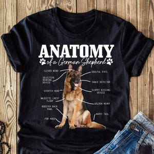Peut inclure: Un t-shirt noir avec un graphique blanc d'un chien berger allemand avec des caractéristiques anatomiques étiquetées. Le texte "Anatomy of a German Shepherd" est en haut du graphique.