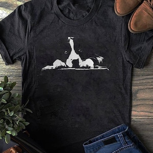 Könnte beinhalten: Ein schwarzes T-Shirt mit einer weißen Silhouette eines Border Collies, der über eine Oberfläche schaut. Die Augen des Hundes sind sichtbar.
