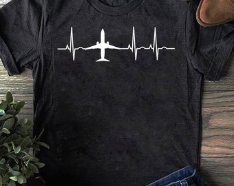 May include: A black t-shirt with a white airplane graphic and a heartbeat line. The graphic is centered on the shirt.
