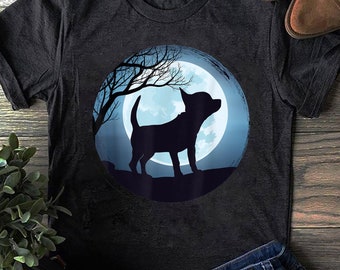 Puede incluir: Una camiseta gris oscura con la silueta de un chihuahua de pie frente a una luna azul. La luna está rodeada por una rama de árbol oscura.