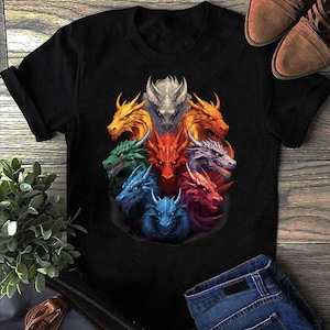 May include: Black t-shirt featuring a vibrant graphic of eight dragon heads in various colors, including gold, green, red, and blue. The dragon heads are arranged in a circular pattern. The shirt is made of a soft material.