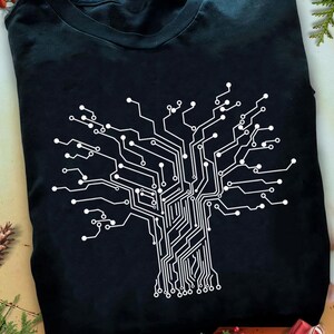 Op de afbeelding: Zwart T-shirt met een wit printplaatontwerp in de vorm van een boom. De afbeelding toont een gedetailleerd, onderling verbonden patroon, dat lijkt op de takken en wortels van een boom. Het shirt is gemaakt van een zacht materiaal.