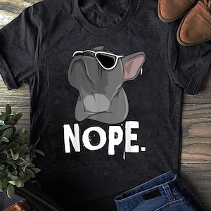 以下が含まれることがあります： 黒いTシャツに、サングラスをかけたフレンチブルドッグの漫画の画像と、白い文字で「NOPE」と書かれています。