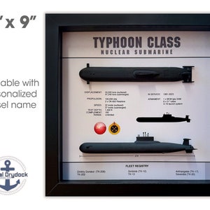 May include: A framed print of a Typhoon Class nuclear submarine with a black frame and a white background. The print includes the submarine's specifications, such as displacement, propulsion, speed, test depth, complement, and range. The print also includes a fleet registry with the names of the submarines in the class.