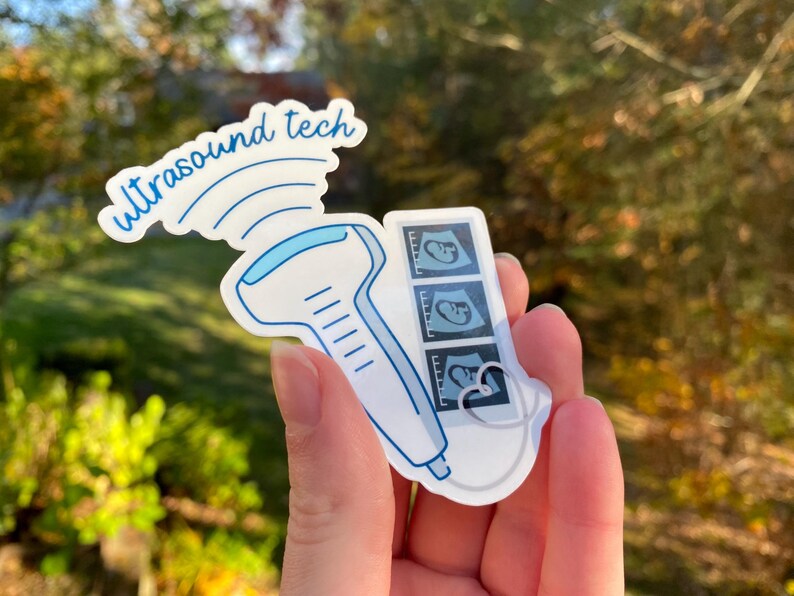 May include: A white sticker with a blue ultrasound wand and the text "ultrasound tech" above it. The wand is connected to a white cord that leads to a small white rectangle with three black and white ultrasound images of a fetus.