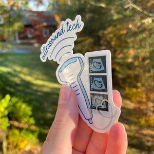 May include: A white sticker with a blue ultrasound wand and three black and white ultrasound images. The sticker says "ultrasound tech" in blue cursive.