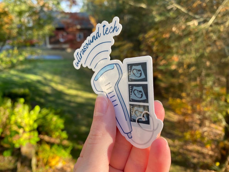 May include: A white sticker with a blue ultrasound wand and three black and white ultrasound images. The sticker says "ultrasound tech" in blue cursive.
