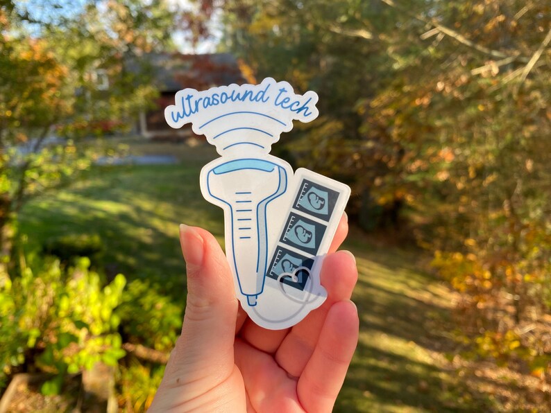 May include: A white sticker with a blue outline of an ultrasound wand and a strip of three ultrasound images. The sticker says "ultrasound tech" in blue cursive.