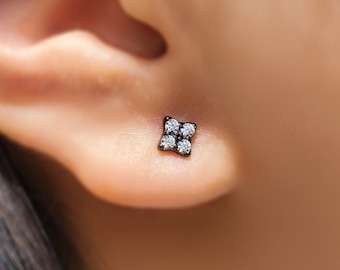 May include: A close-up of a black diamond stud earring with four small diamonds set in a square shape.