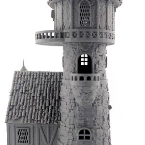 May include: A gray miniature castle tower with a detailed stone facade, a conical roof, and a small balcony. The tower features arched windows and a textured roof, perfect for tabletop gaming or model enthusiasts.
