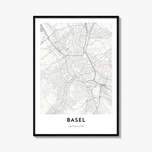 May include: A framed wall art print featuring a detailed grey and white street map of Basel, Switzerland. The map displays intricate road networks and a river flowing through the city. The text BASEL SWITZERLAND is printed in black at the bottom.