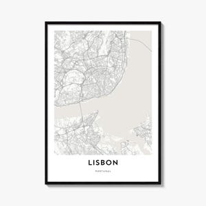 May include: A framed wall art print featuring a detailed street map of Lisbon, Portugal. The map displays grey road networks against a light beige background, with the text LISBON PORTUGAL printed in bold black capital letters at the bottom.