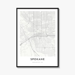May include: A framed wall art print featuring a detailed grey and white street map of Spokane, Washington, USA. The design displays a grid of city streets, highways, and a river, with the text SPOKANE WASHINGTON, USA printed at the bottom.