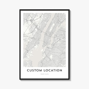 May include: A framed wall art print featuring a detailed grey and white street map of a city. The design includes the text CUSTOM LOCATION in bold black capital letters, followed by the smaller text YOUR PLACE centered at the bottom.