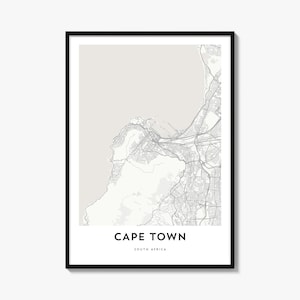 May include: A framed wall art print featuring a minimalist map of Cape Town, South Africa. The design displays grey street lines against a light beige background, with the text CAPE TOWN and SOUTH AFRICA printed in black at the bottom center.
