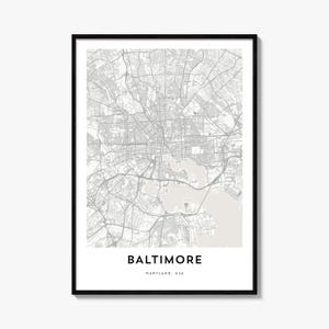 May include: A framed wall art print featuring a detailed street map of Baltimore, Maryland, USA. The map displays grey road networks against a light beige background, with the text BALTIMORE and MARYLAND, USA printed in black at the bottom.