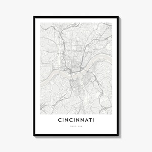 May include: A framed wall art print featuring a detailed street map of Cincinnati, Ohio, USA. The map displays grey road networks and a light beige river path on a white background. The text CINCINNATI OHIO, USA is printed in black at the bottom.