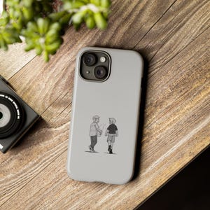 May include: A white phone case with a black and white illustration of two people walking and talking. The phone case has a camera lens cutout.
