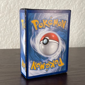 May include: A blue and white Pokemon trading card box with the Pokemon logo and a Pokeball graphic.