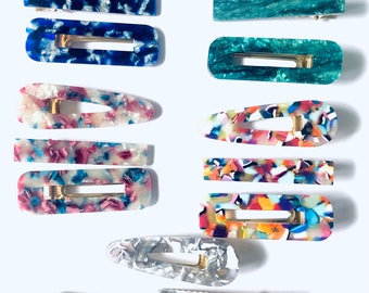 May include: Assortment of 10 colorful hair clips with a tortoise shell pattern. The clips are made of plastic and have a gold metal spring.