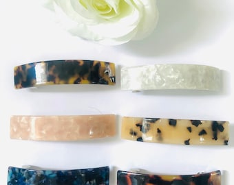 May include: Six different hair clips in various colors and patterns. The clips are made of a tortoiseshell-like material and have a curved shape.