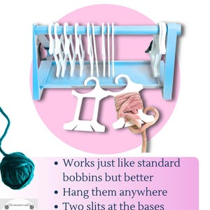 Pode incluir: Um suporte de bobinas suspenso de madeira azul claro com bobinas brancas. O texto "HANGING BOBBINS" está no topo. O texto "Works just like standard bobbins but better" também é visível.