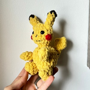 Op de afbeelding: Een gehaakt geel Pikachu knuffeldier met zwarte oren en rode wangen.
