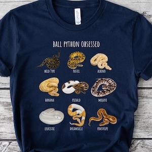 Peut inclure: T-shirt bleu marine avec l'inscription "BALL PYTHON OBSESSED" et des illustrations de différentes couleurs de pythons royaux, dont Wild Type, Pastel, Albino, Banana et Mojave. Le t-shirt est en matière douce.