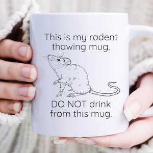May include: White ceramic mug with a black and white illustration of a rat and the text "This is my rodent thawing mug. DO NOT drink from this mug."
