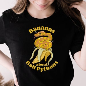 May include: A black t-shirt with a yellow banana and a snake wrapped around it. The text "Bananas about Ball Pythons" is printed on the shirt.