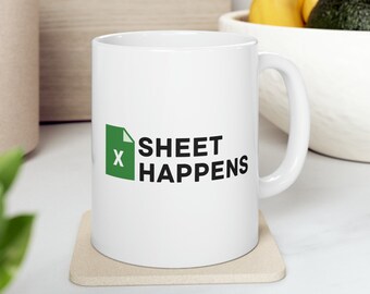 Könnte beinhalten: Eine weiße Keramiktasse mit einem grün-schwarzen Logo, auf dem "X SHEET HAPPENS" steht. Die Tasse steht auf einem beigefarbenen Untersetzer.