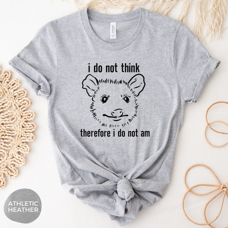 May include: A grey t-shirt with a black and white illustration of an opossum with the text "i do not think therefore i do not am"
